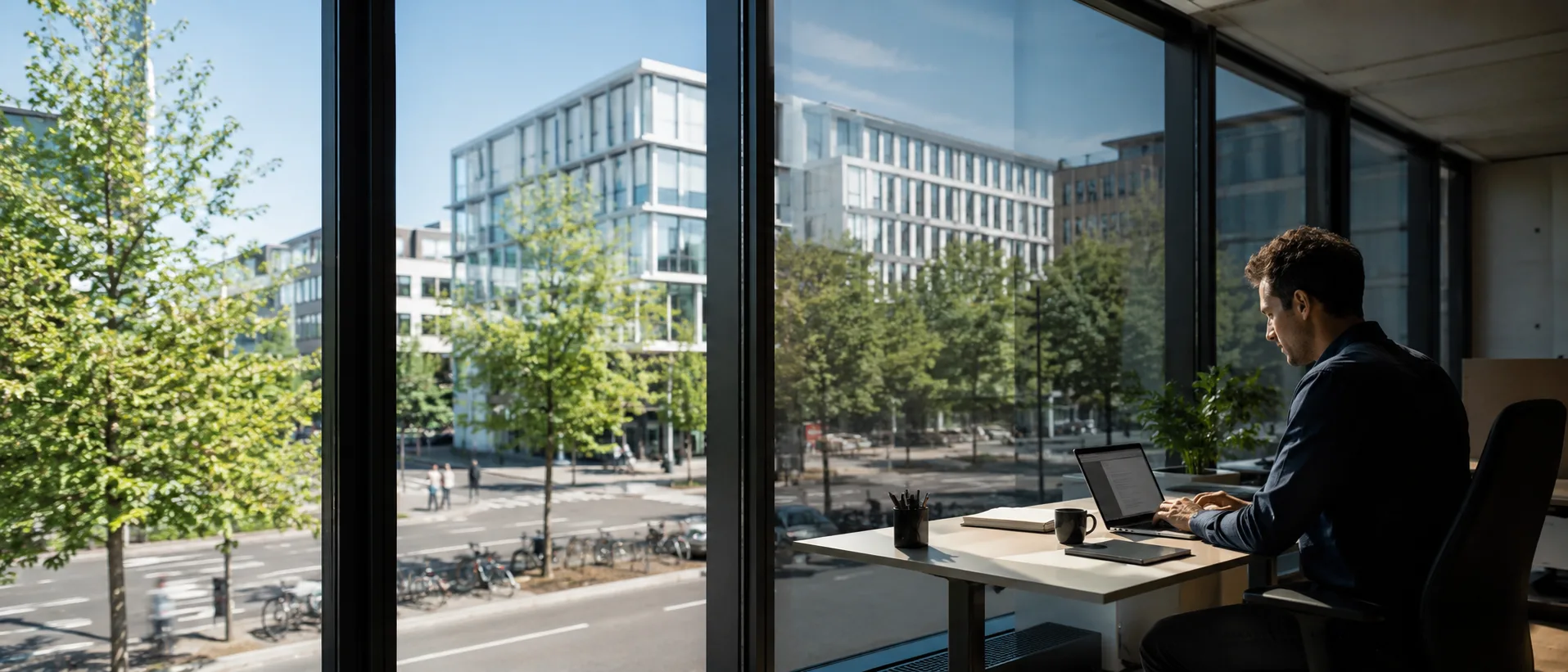 Mitarbeiter arbeitet am Schreibtisch ohne Blendlicht, Sonne draußen