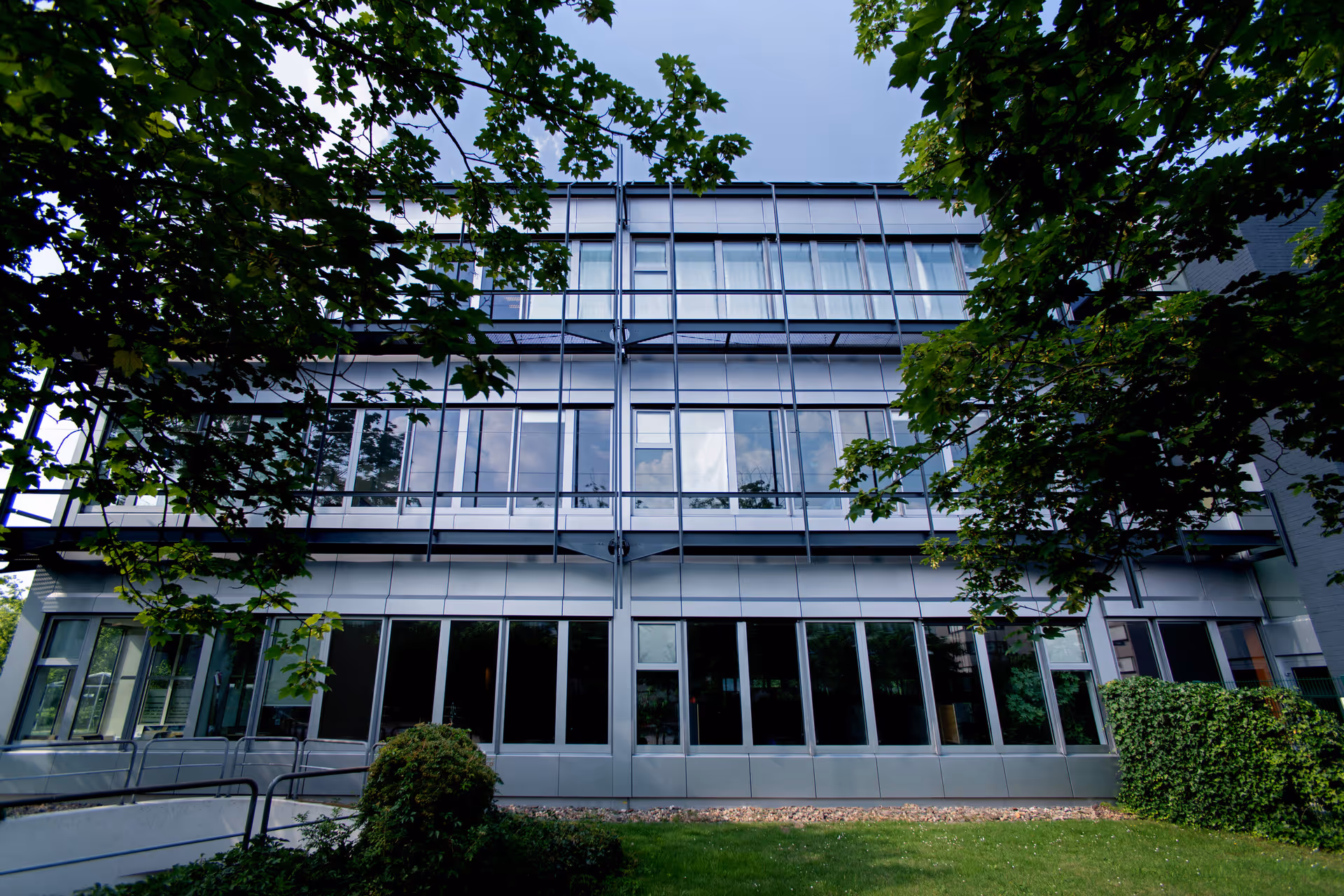 Foliertes Bürogebäude im Hive Park Ratingen mit metallisch silbriger Kassettenfassade, davor Bäume