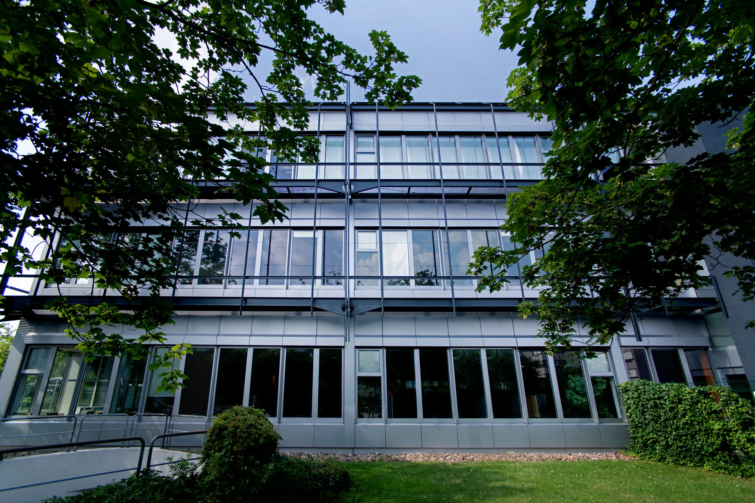 Foliertes Bürogebäude im Hive Park Ratingen mit metallisch silbriger Kassettenfassade, davor Bäume